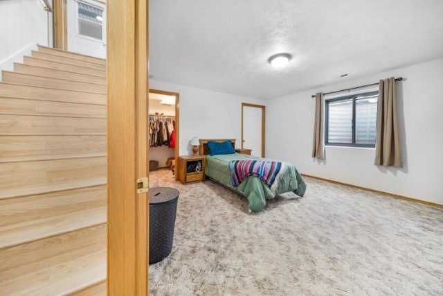 bedroom with carpet, a closet, a spacious closet, and baseboards