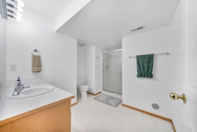 bathroom featuring toilet, vanity, visible vents, a shower stall, and tile patterned floors