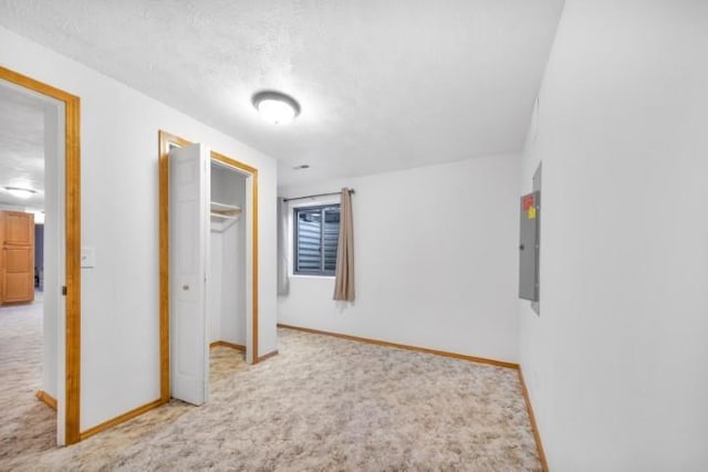 unfurnished bedroom with carpet floors, electric panel, baseboards, and a closet