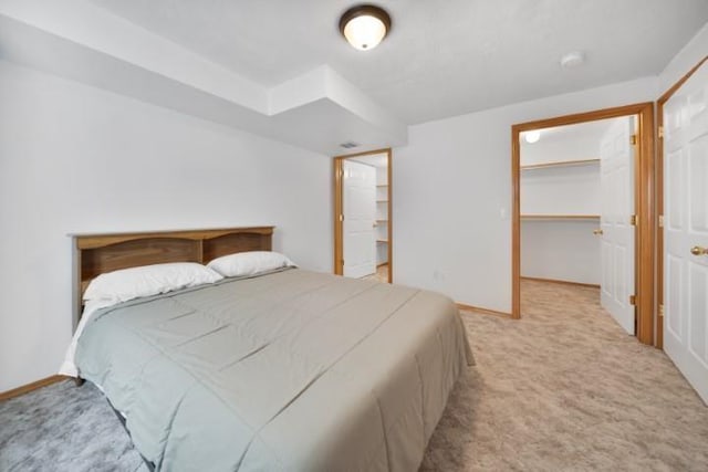 carpeted bedroom featuring visible vents, a spacious closet, baseboards, and a closet