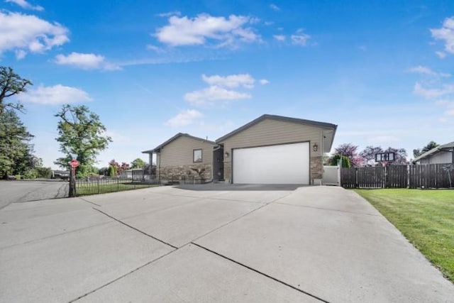 view of front of property with a garage, concrete driveway, stone siding, fence, and a front yard