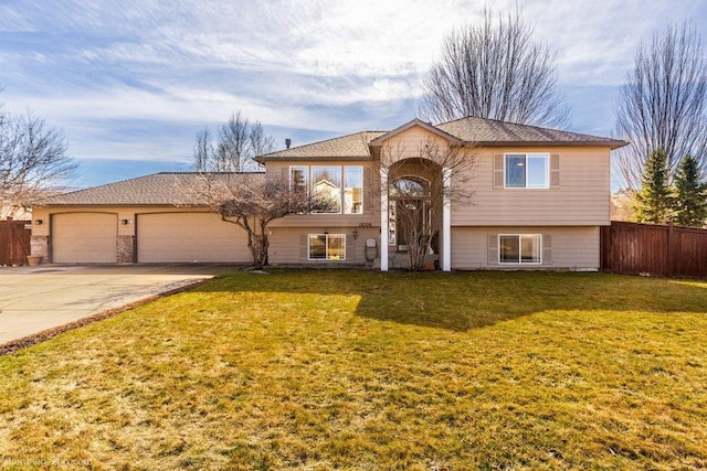 split foyer home with a garage, driveway, a front lawn, and fence