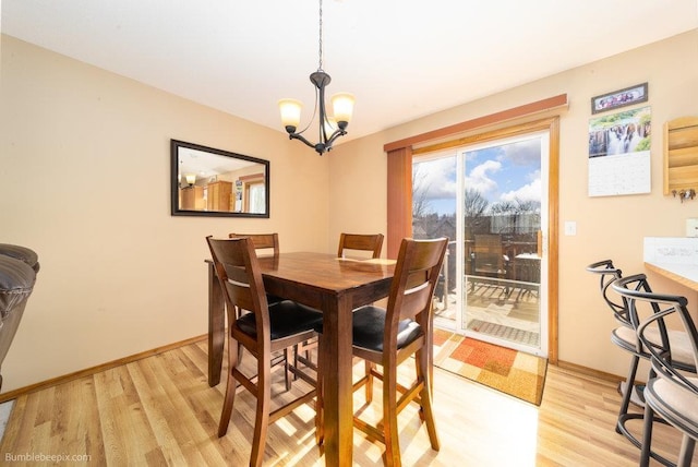 dining space featuring light wood finished floors, baseboards, and a chandelier