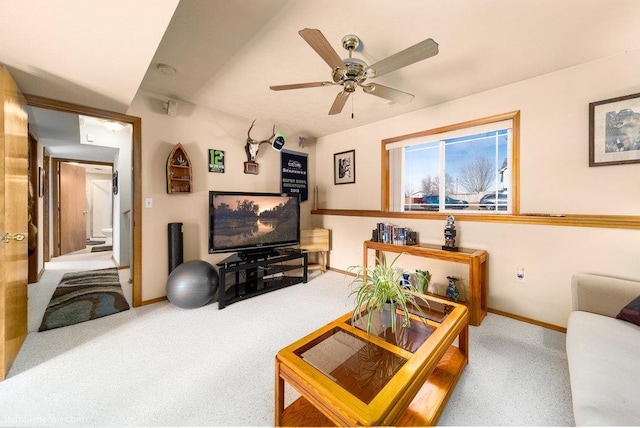 carpeted living area with ceiling fan and baseboards