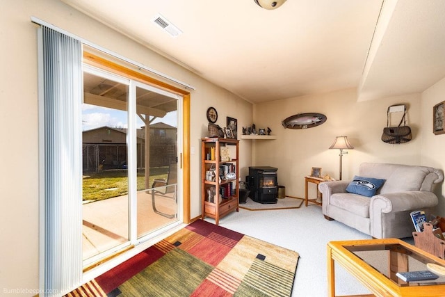 carpeted living room featuring a wood stove and visible vents