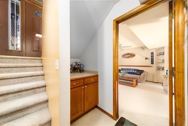 stairway with carpet, baseboards, vaulted ceiling, and a textured ceiling