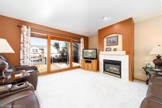 living area featuring baseboards, a fireplace, and light colored carpet