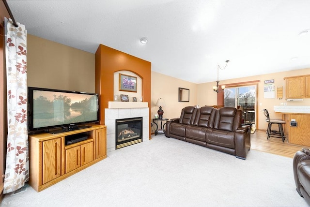 living area with light carpet, a notable chandelier, and a tiled fireplace