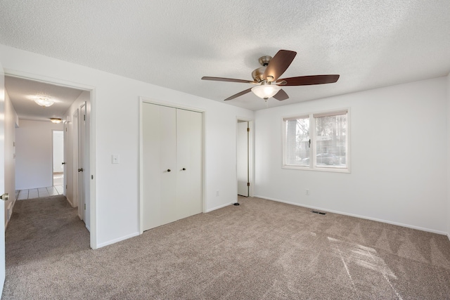 unfurnished bedroom with visible vents, a ceiling fan, a textured ceiling, carpet floors, and a closet