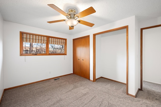 unfurnished bedroom featuring carpet floors, a closet, visible vents, a textured ceiling, and baseboards