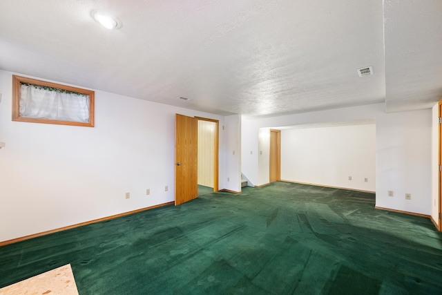 carpeted empty room featuring baseboards, visible vents, and a textured ceiling