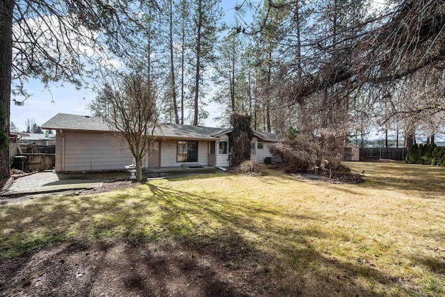 rear view of house with fence and a yard