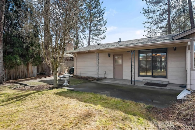 back of property with a patio, a lawn, a chimney, and fence