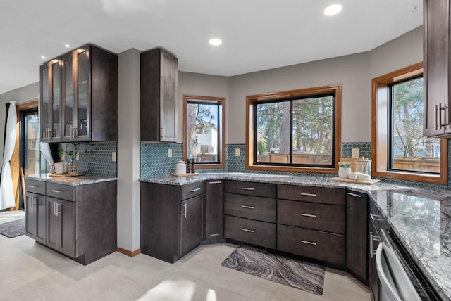 kitchen featuring dark brown cabinetry, backsplash, light stone countertops, dishwasher, and glass insert cabinets