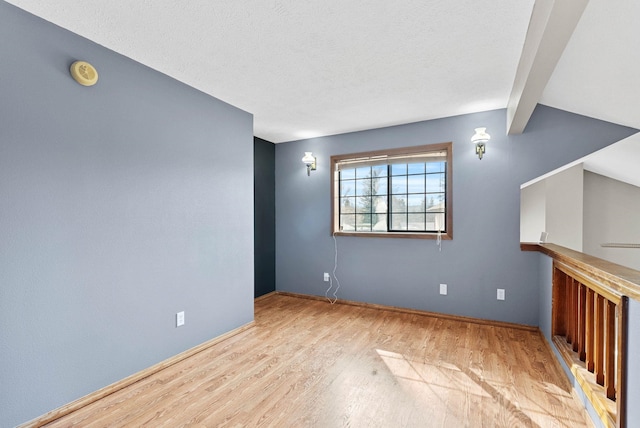 unfurnished living room with lofted ceiling with beams, a textured ceiling, and wood finished floors