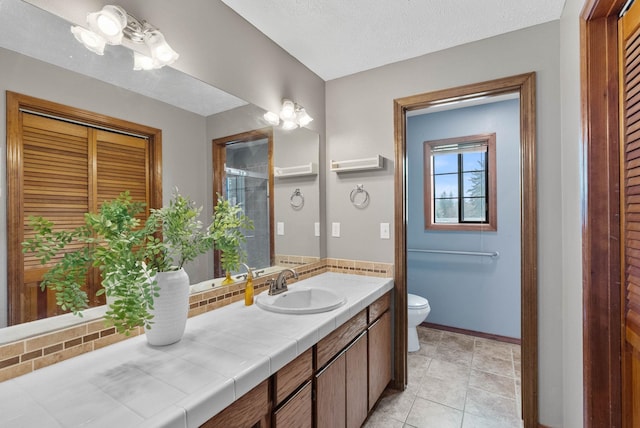 bathroom featuring baseboards, toilet, tile patterned flooring, a textured ceiling, and vanity