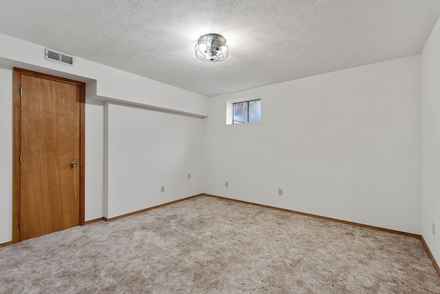 empty room featuring a textured ceiling, carpet flooring, visible vents, and baseboards