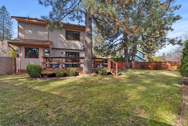 back of house featuring a deck, a lawn, and a fenced backyard