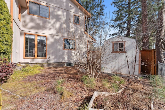 view of side of home featuring a storage shed, fence, and an outdoor structure