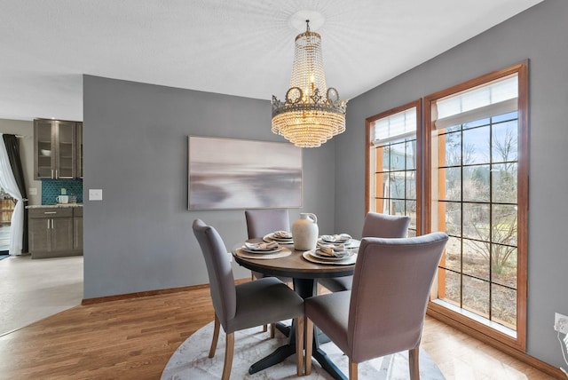 dining space featuring baseboards, light wood-style flooring, and an inviting chandelier