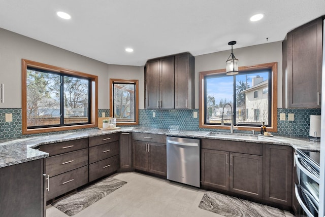 kitchen with dark brown cabinets, light stone counters, stainless steel appliances, and a sink