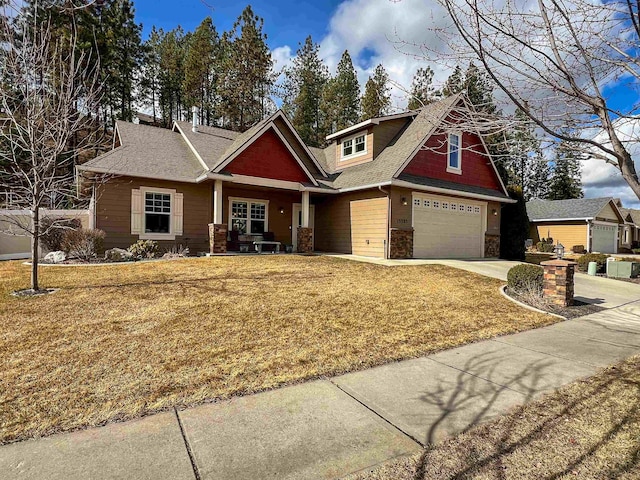 craftsman-style home featuring a garage, concrete driveway, a front lawn, and stone siding