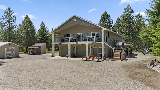 back of house featuring a garage, an outdoor structure, stairway, a shed, and gravel driveway