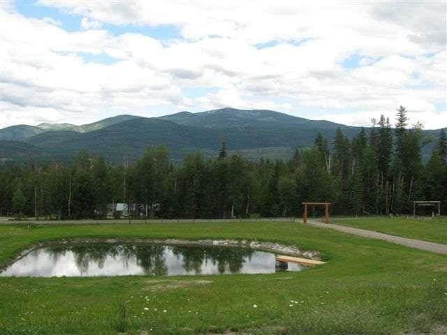 surrounding community with a forest view, a lawn, and a water and mountain view