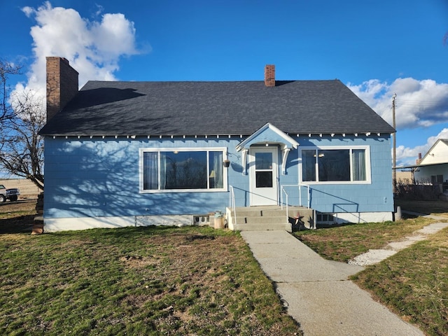 bungalow-style home with roof with shingles, a front lawn, and a chimney