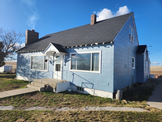 bungalow-style home with roof with shingles and a chimney