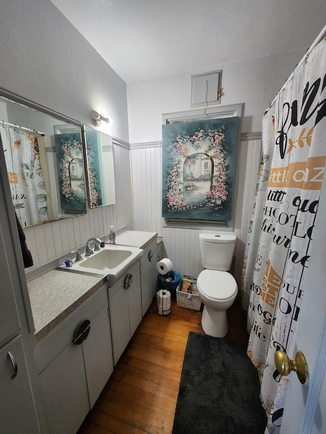 full bathroom featuring wainscoting, toilet, wood finished floors, curtained shower, and vanity