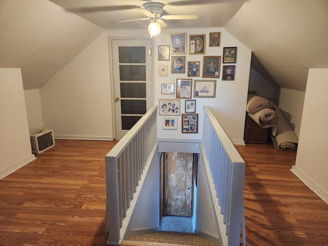 corridor featuring heating unit, vaulted ceiling, wood finished floors, and an upstairs landing