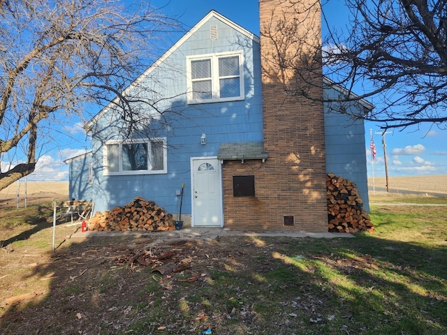 exterior space featuring a yard, a shingled roof, and a chimney