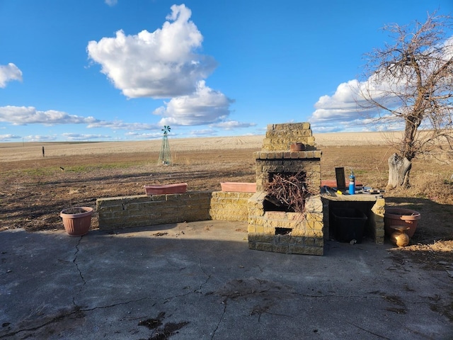 view of patio / terrace featuring a rural view and an outdoor stone fireplace