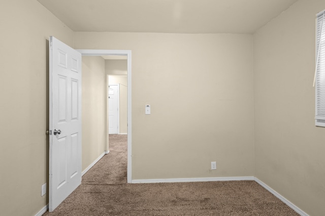 unfurnished room with carpet flooring and baseboards