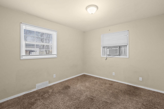 carpeted empty room with cooling unit, visible vents, and baseboards