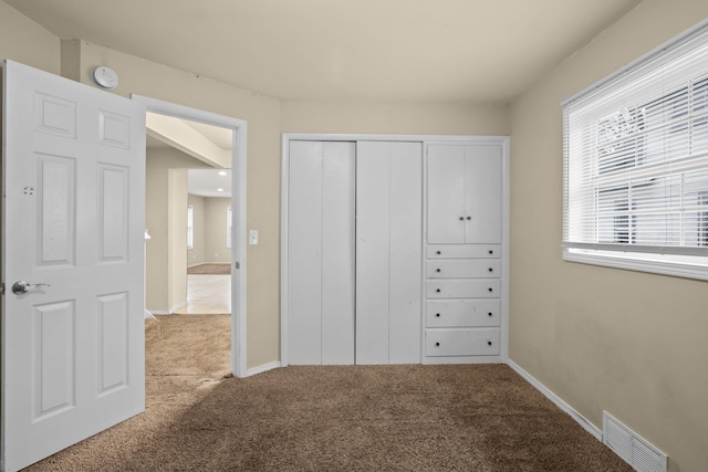 unfurnished bedroom featuring a closet, carpet flooring, visible vents, and baseboards