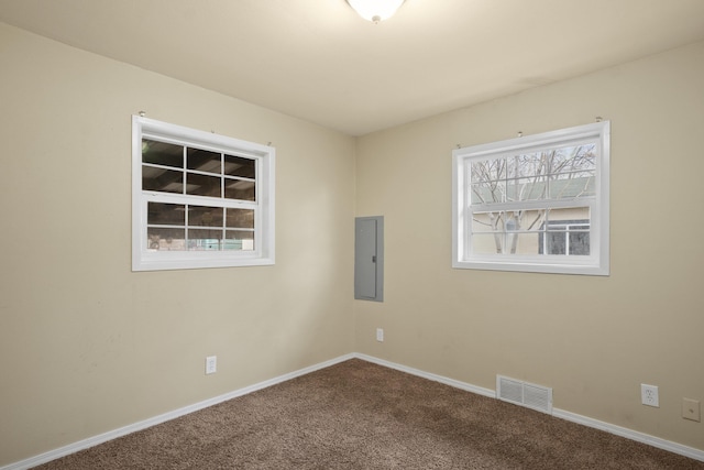 carpeted spare room featuring baseboards, electric panel, and visible vents