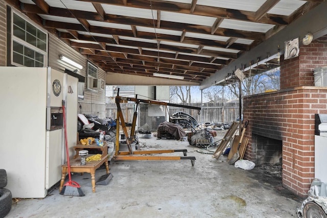 garage with freestanding refrigerator and fence