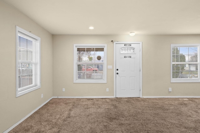 entryway featuring plenty of natural light, baseboards, and carpet flooring