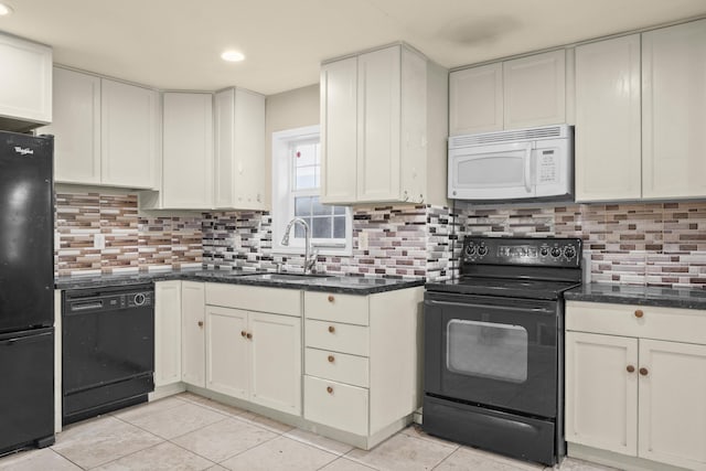 kitchen featuring light tile patterned floors, tasteful backsplash, a sink, dark stone countertops, and black appliances