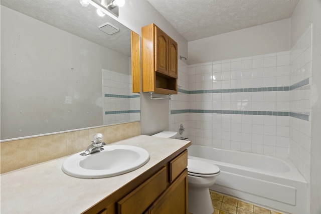 bathroom with a textured ceiling, shower / washtub combination, vanity, and toilet