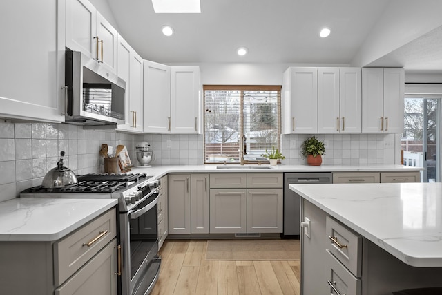 kitchen with light wood-type flooring, stainless steel appliances, a sink, and gray cabinetry