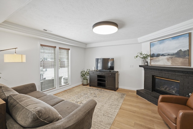 living area featuring light wood-style flooring, a fireplace, baseboards, and a textured ceiling