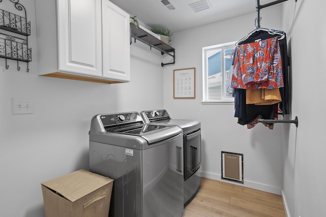 laundry area featuring light wood-style floors, visible vents, cabinet space, and washer and clothes dryer