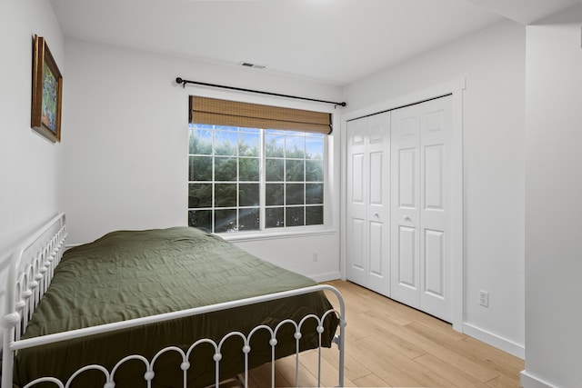 bedroom featuring light wood finished floors, a closet, visible vents, and baseboards