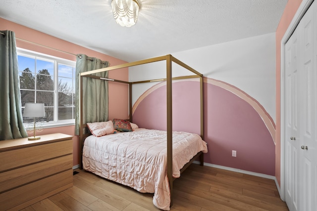 bedroom featuring a textured ceiling, hardwood / wood-style floors, a closet, and arched walkways