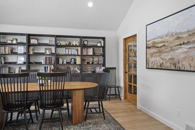 interior space with light wood-style floors, baseboards, visible vents, and vaulted ceiling