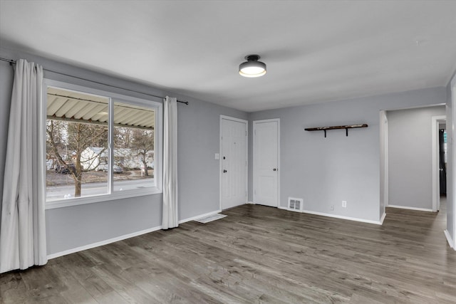 unfurnished room with baseboards, visible vents, and wood finished floors