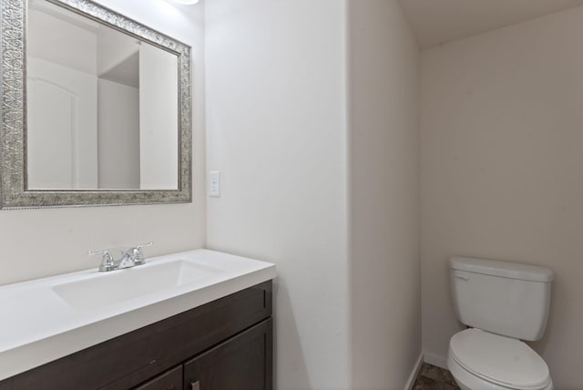 bathroom with vanity, toilet, and baseboards